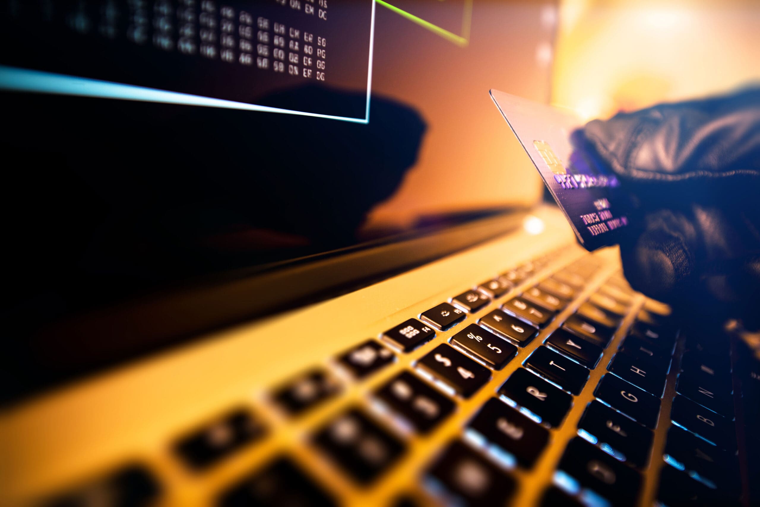 Gloved hand holding credit card near laptop